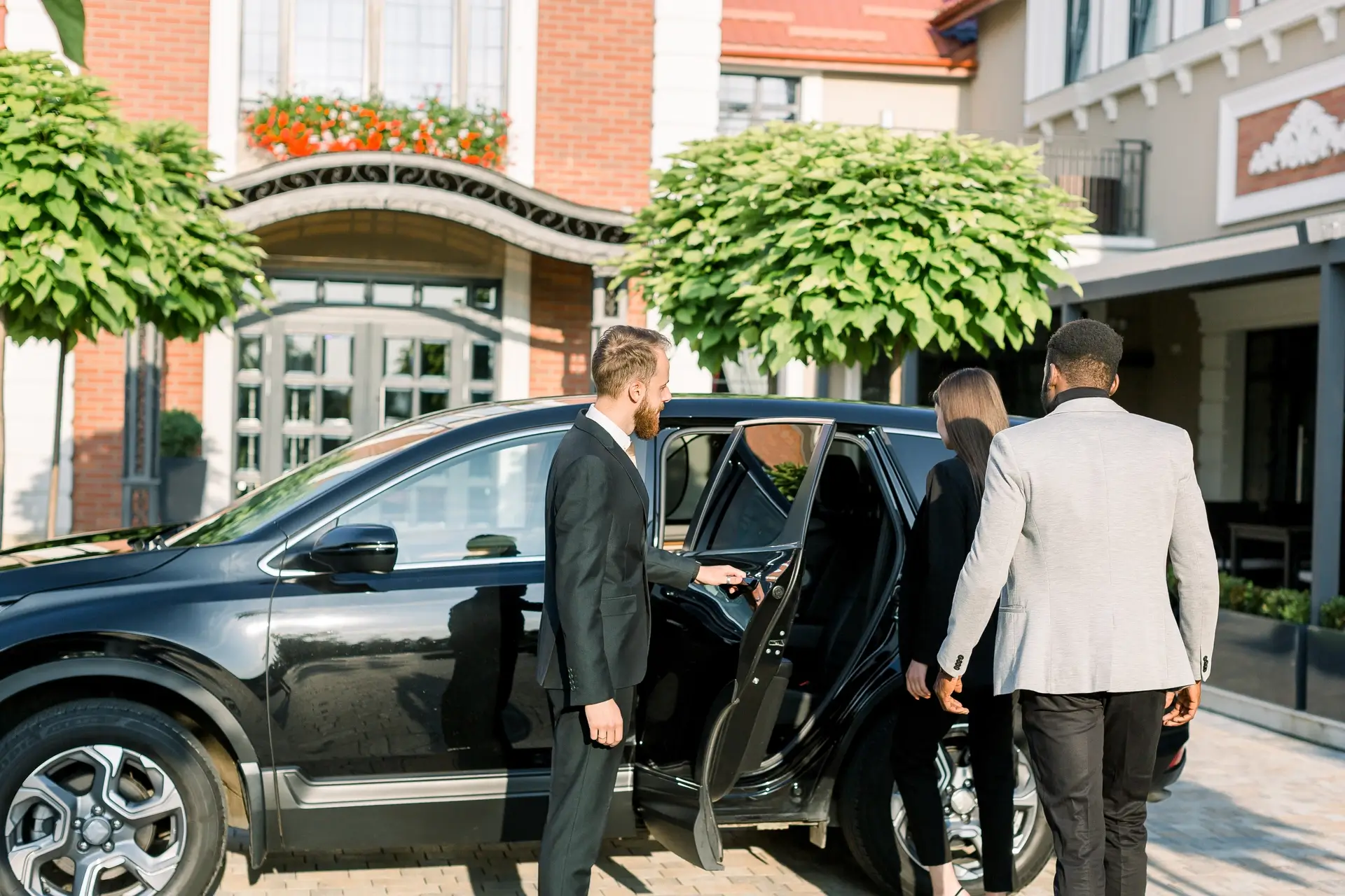 chauffeur-man-opening-car-door-for-business-couple-2021-09-04-16-23-16-utc